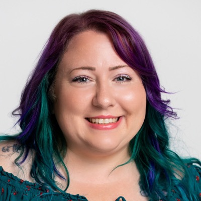 Sam, smiling, with purple and teal hair